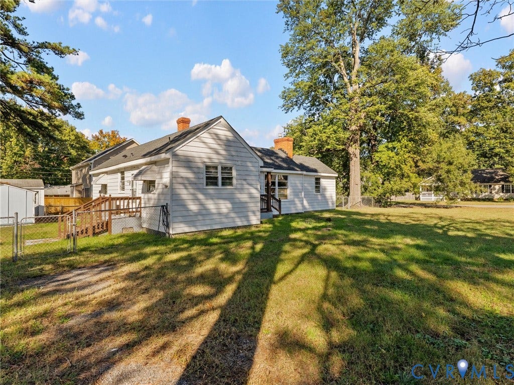 2900 Overton Road, Henrico, VA 23228 Exterior featuring light-toned horizontal siding, two brick chimneys, an elevated wooden deck, and a spacious lot with mature trees