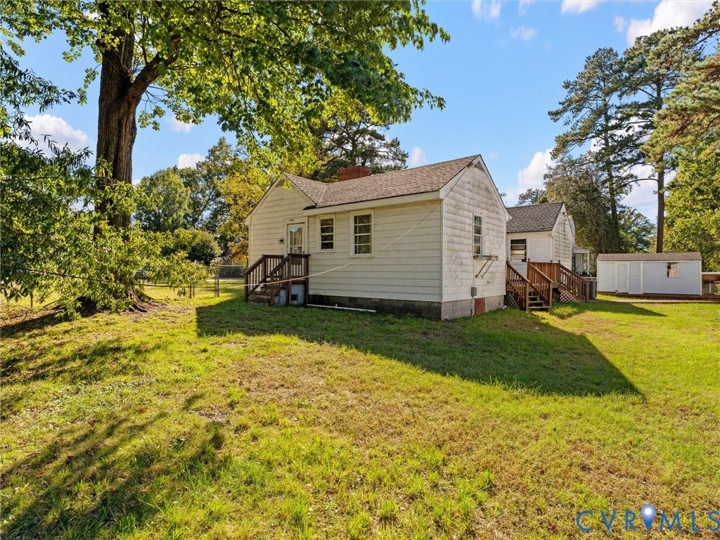 2900 Overton Road, Henrico, VA 23228 Single-story residence featuring light-colored horizontal siding, dual wood-frame exterior staircases, a brick chimney, and a detached storage structure on a spacious lot with mature trees