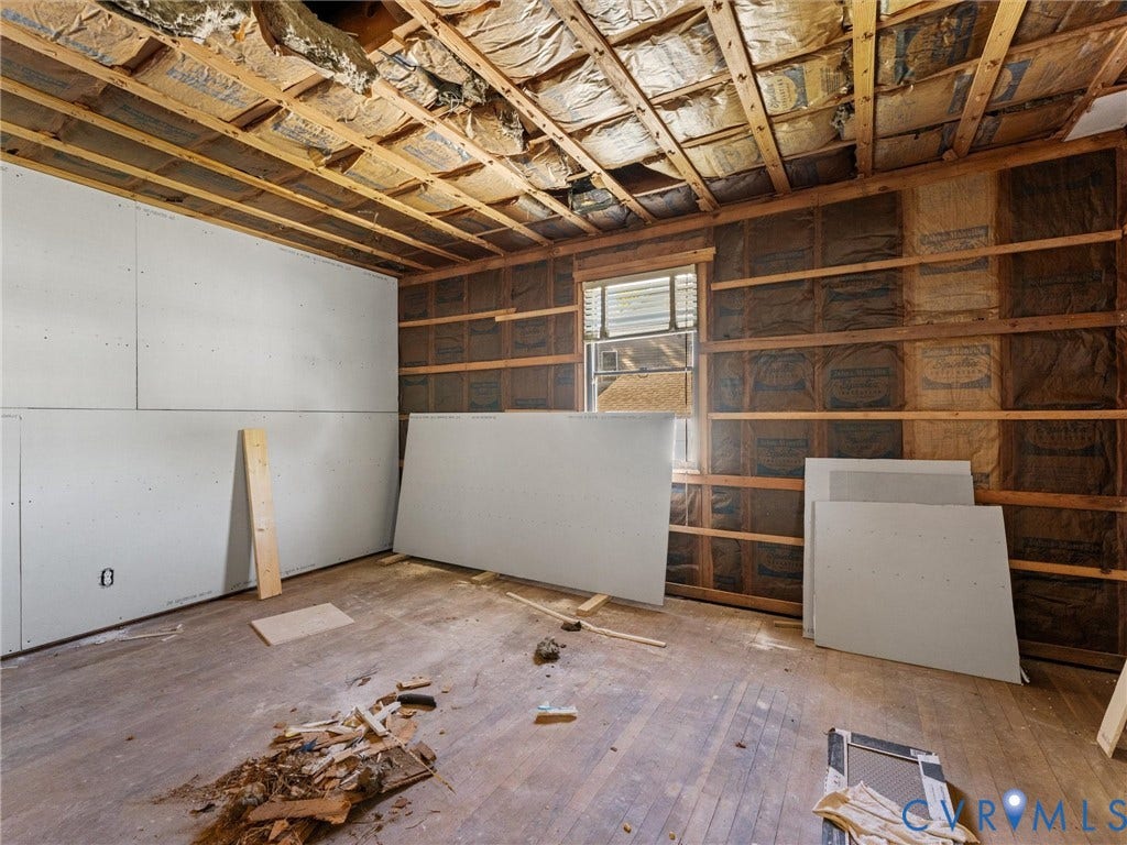 2900 Overton Road, Henrico, VA 23228 Interior space featuring exposed wood-stud wall framing, partial drywall installation, exposed ceiling joists with insulation, and original wood-finish flooring