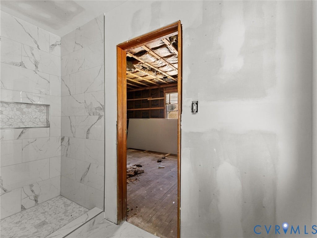 2900 Overton Road, Henrico, VA 23228 Shower enclosure featuring large-format veined tile walls, hexagonal inset tile niche, and natural wood-finish door casing