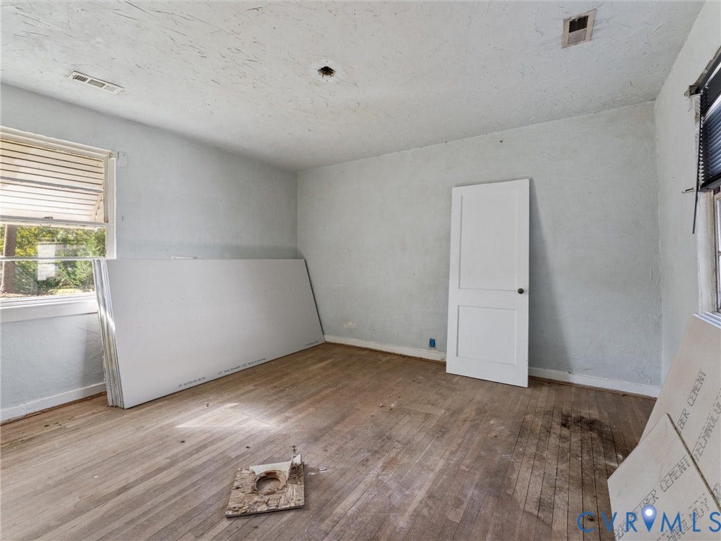 2900 Overton Road, Henrico, VA 23228 Room interior featuring wood-finish flooring, a two-panel solid core door, and windows with integrated blinds