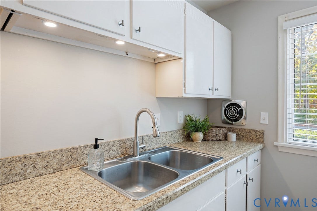 9131 Derbyshire Road, #B, Deerwood Condominiums, Henrico, VA 23229 Kitchen area featuring speckled stone countertops, dual-basin stainless steel sink with high-arc faucet, white cabinetry, under-cabinet lighting, and an integrated exhaust fan