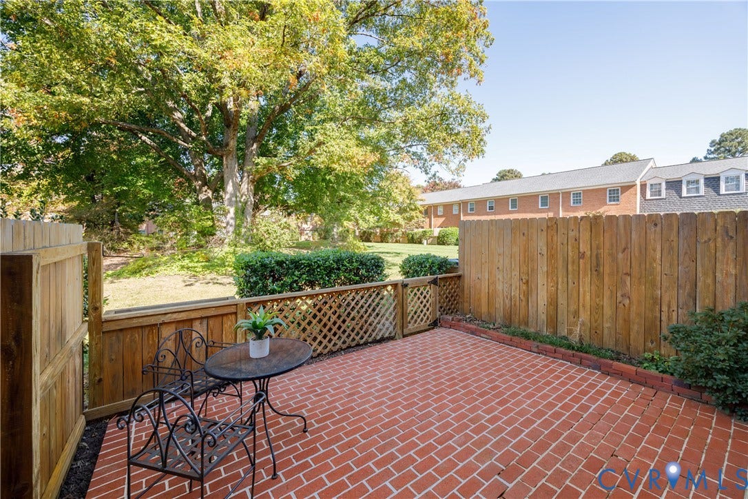 9131 Derbyshire Road, #B, Deerwood Condominiums, Henrico, VA 23229 Private brick patio enclosed by a wood-slat fence with integrated lattice detailing and mature surrounding trees