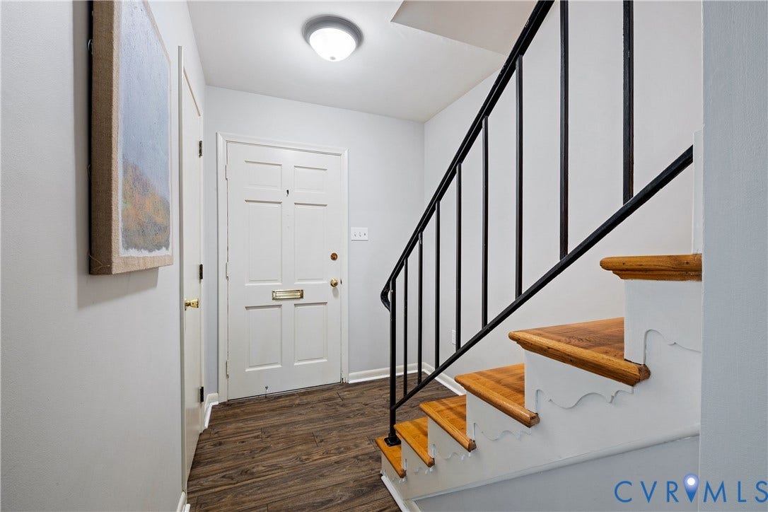 9131 Derbyshire Road, #B, Deerwood Condominiums, Henrico, VA 23229 Foyer featuring wood-finish flooring, a white panel door with brass hardware, a staircase with wood treads and decorative risers, a black metal handrail, and a flush-mount ceiling light fixture
