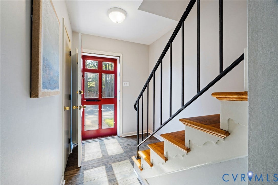 9131 Derbyshire Road, #B, Deerwood Condominiums, Henrico, VA 23229 Entryway featuring a red paneled front door with glass inserts, wood-finish flooring, and a staircase with stained wood treads and a black metal railing