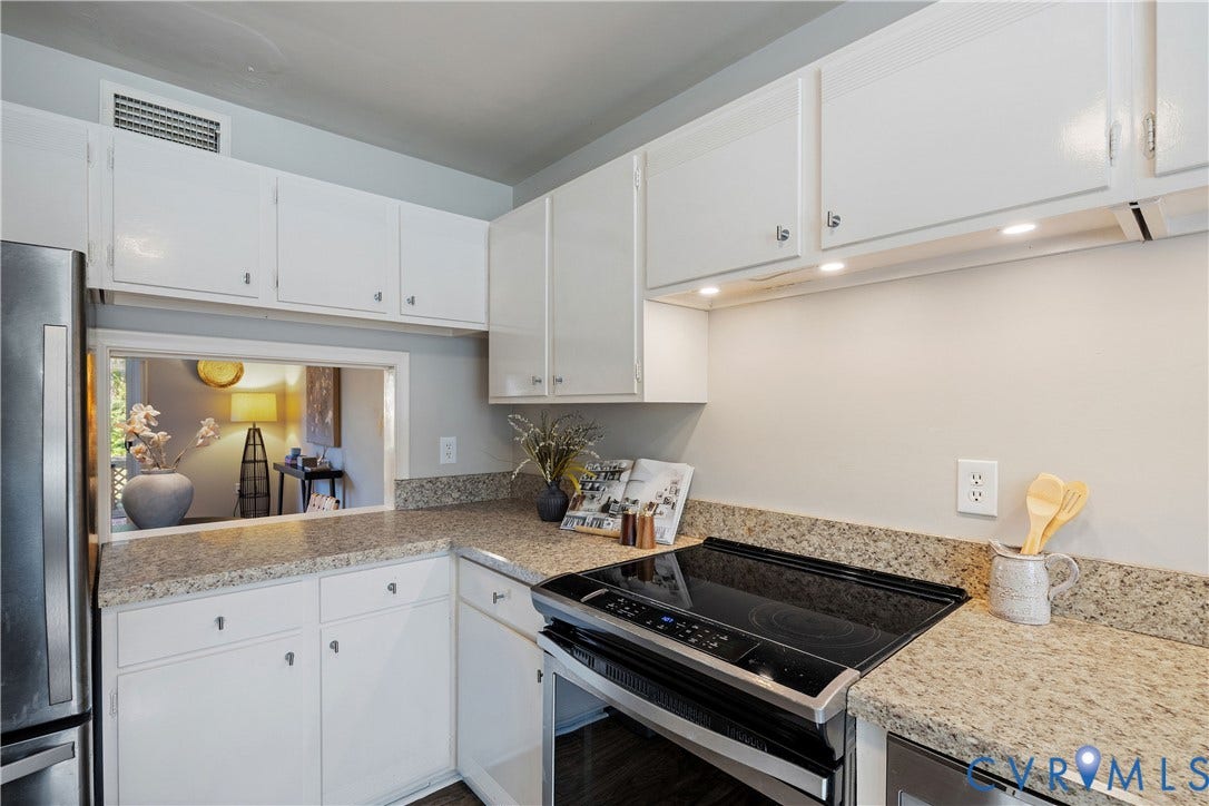 9131 Derbyshire Road, #B, Deerwood Condominiums, Henrico, VA 23229 Kitchen featuring white cabinetry, stone-finish countertops, stainless steel appliances, and a pass-through opening