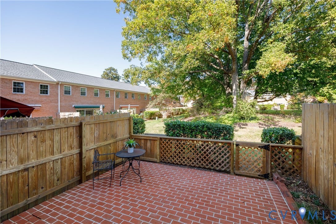 9131 Derbyshire Road, #B, Deerwood Condominiums, Henrico, VA 23229 Red brick patio featuring a wood privacy fence, lattice detailing, and a gated entrance