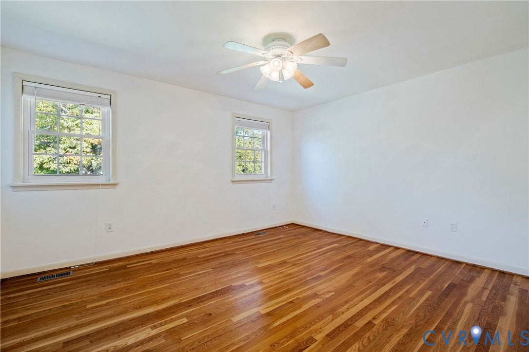 9131 Derbyshire Road, #B, Deerwood Condominiums, Henrico, VA 23229 Interior room featuring wood-finish flooring, two multi-pane windows with trim, and a ceiling fan with integrated lighting