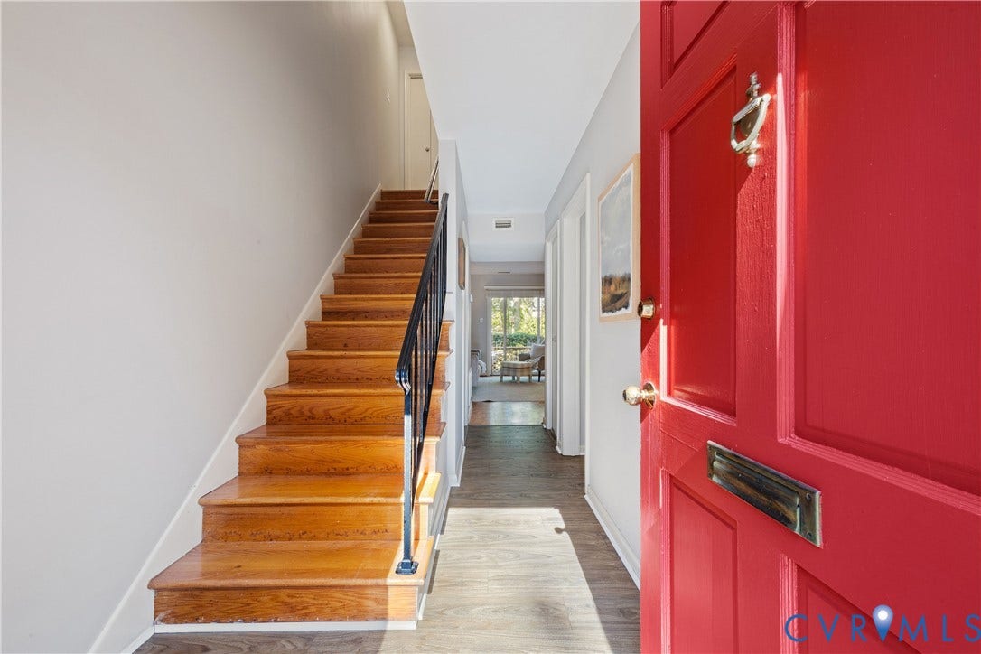 9131 Derbyshire Road, #B, Deerwood Condominiums, Henrico, VA 23229 Entryway featuring a bold red paneled front door, wood-finish staircase with metal balusters, and wood-finish flooring