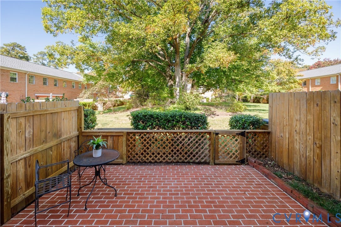 9131 Derbyshire Road, #B, Deerwood Condominiums, Henrico, VA 23229 Private patio featuring brick pavers, a wood privacy fence, and a decorative lattice gate