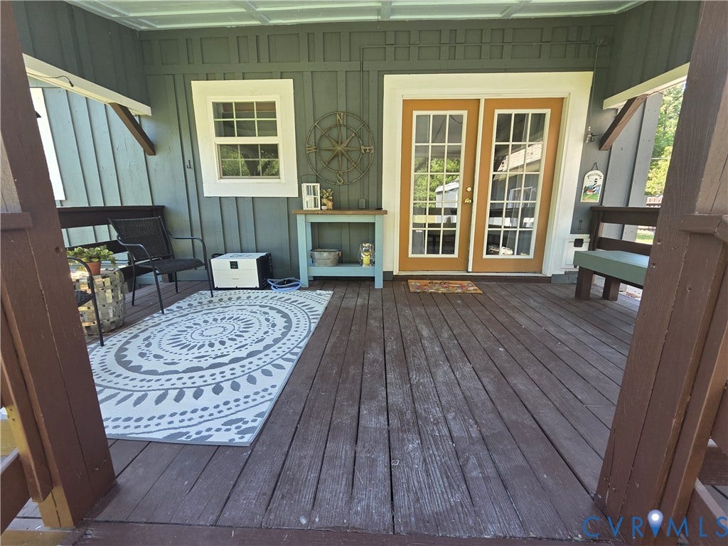 7620 Cypress Drive, Lanexa, VA 23089 Covered wooden deck featuring board and batten siding, glass-paneled double doors, and a multi-pane window