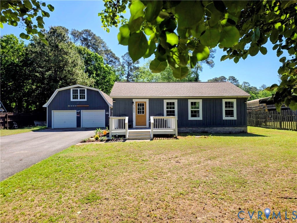 7620 Cypress Drive, Lanexa, VA 23089 Single-story residence featuring vertical siding, stone base detailing, a raised front deck with railing, and a detached two-car garage