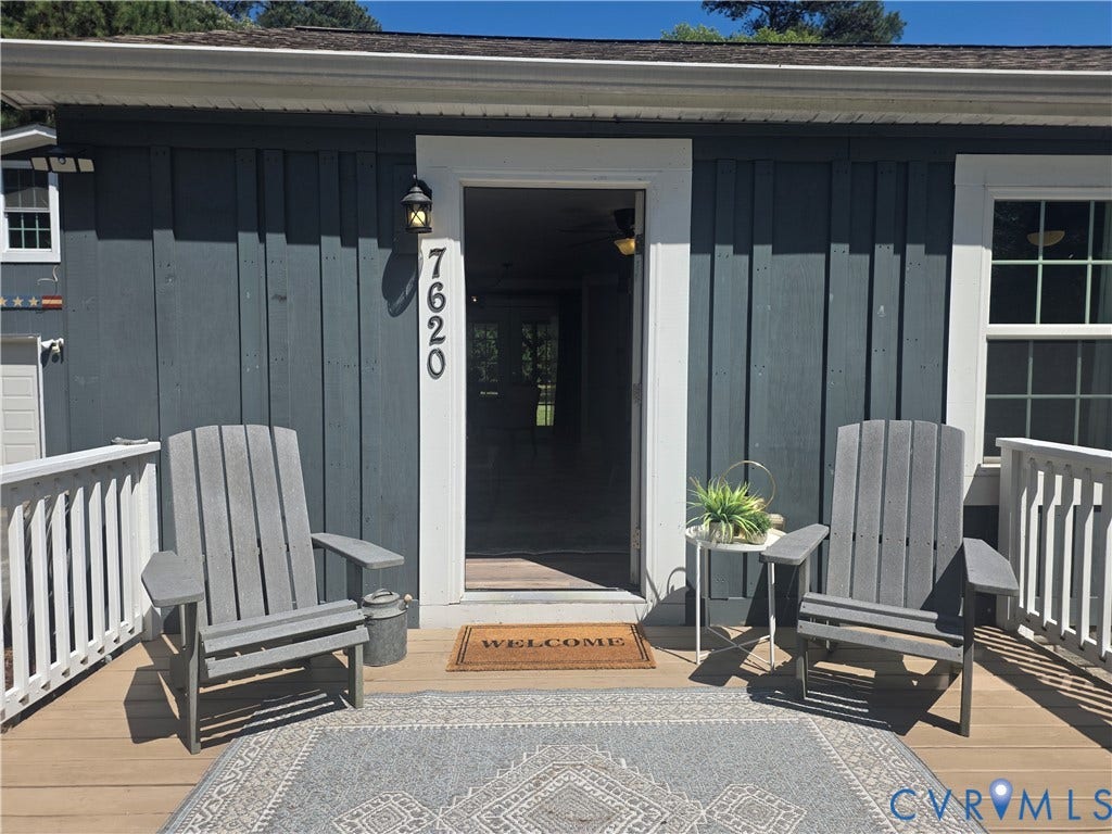 7620 Cypress Drive, Lanexa, VA 23089 Board and batten charcoal siding, crisp white trim, exterior wall-mounted light fixture, and wooden deck with white railing