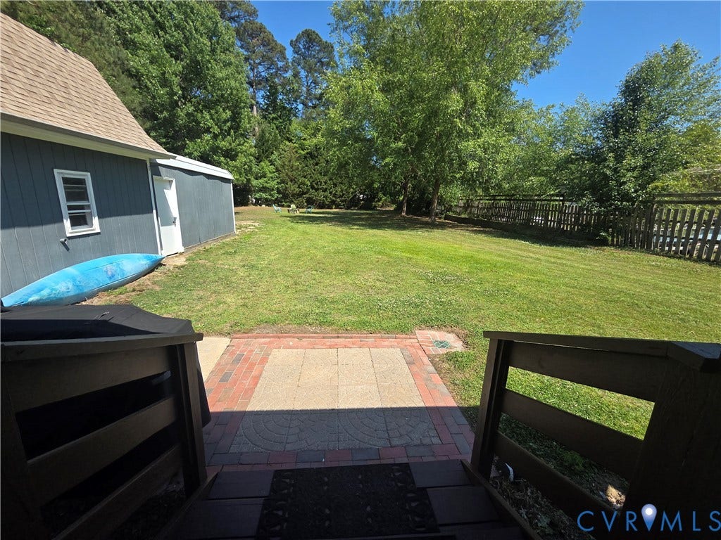 7620 Cypress Drive, Lanexa, VA 23089 Expansive backyard featuring a grass lawn, paved brick and stone patio, wood-railing staircase, and perimeter wood fencing