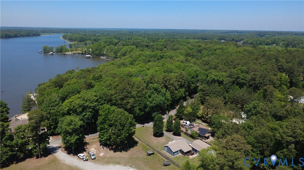 7620 Cypress Drive, Lanexa, VA 23089 Aerial perspective featuring expansive waterfront positioning, mature forest canopy, and a gravel drive