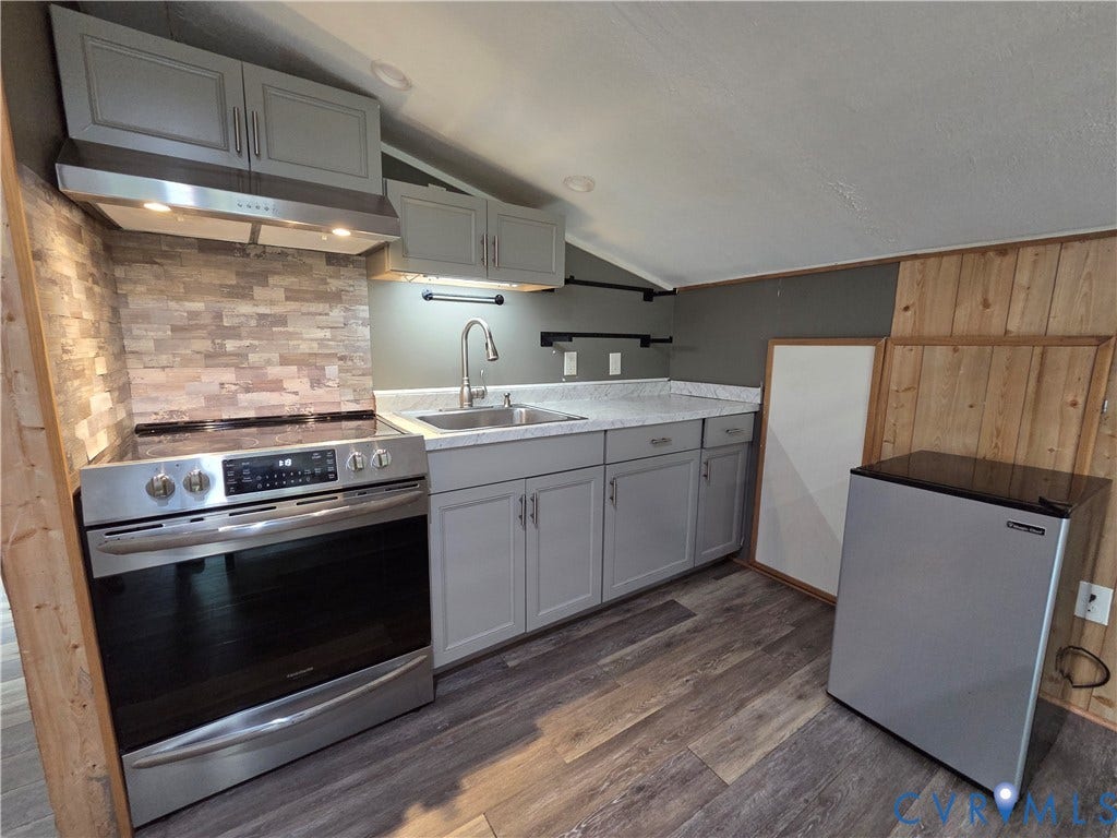 7620 Cypress Drive, Lanexa, VA 23089 Kitchen featuring wood-finish flooring, grey cabinetry, stainless steel range with overhead vent hood, stone-style tile backsplash, and light-toned countertop with integrated sink