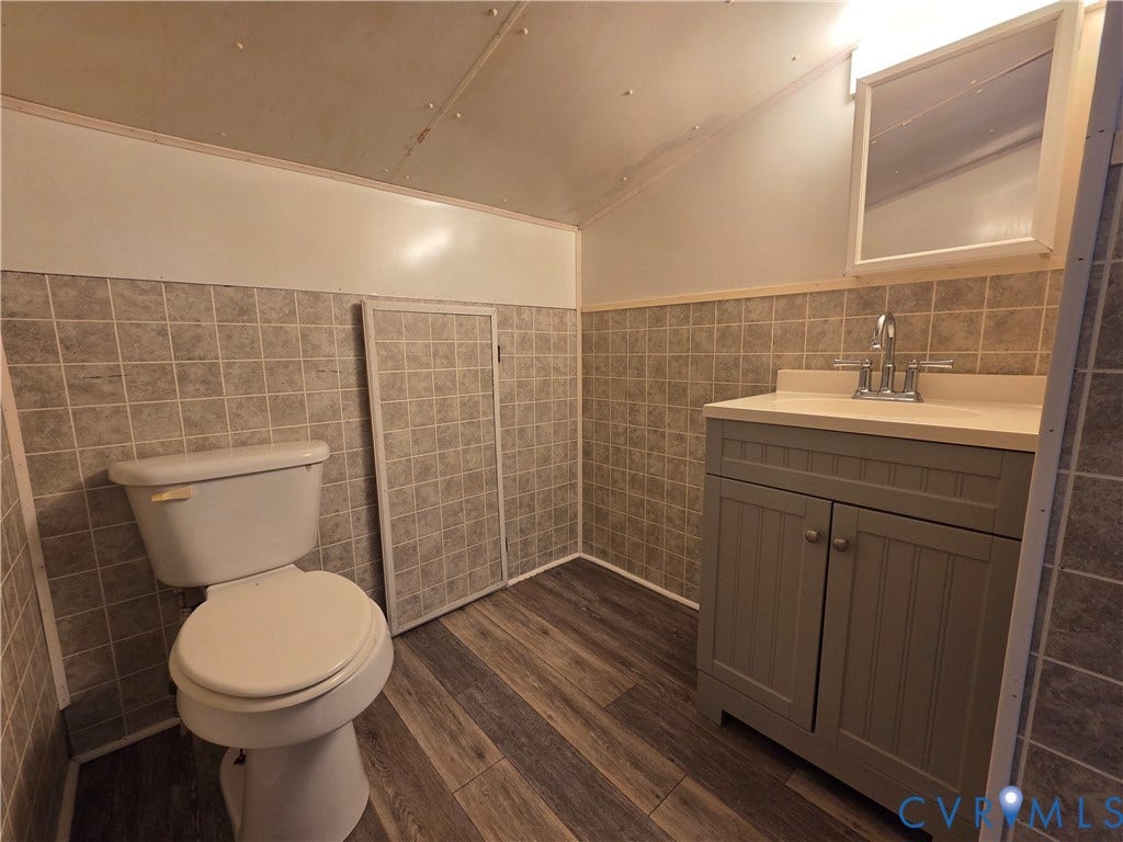 7620 Cypress Drive, Lanexa, VA 23089 Bathroom featuring wood-finish flooring, tiled walls, vanity cabinet with integrated sink, and wall-mounted medicine cabinet