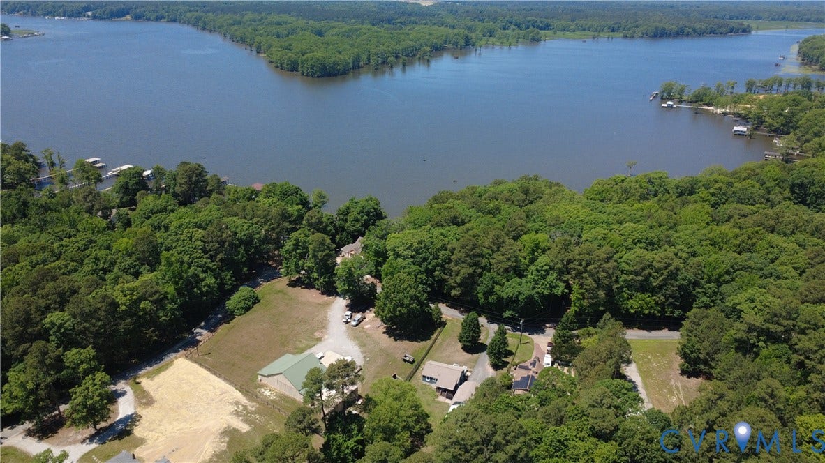7620 Cypress Drive, Lanexa, VA 23089 Aerial perspective of a waterfront property featuring extensive shoreline, dense perimeter woodlands, open clearing, and gravel access driveway