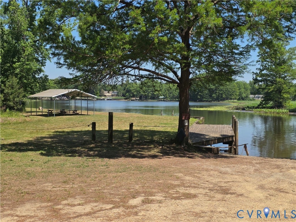 7620 Cypress Drive, Lanexa, VA 23089 Waterfront grounds featuring a private wood-plank dock, metal-roofed pavilion, mature trees, and direct access to the lake