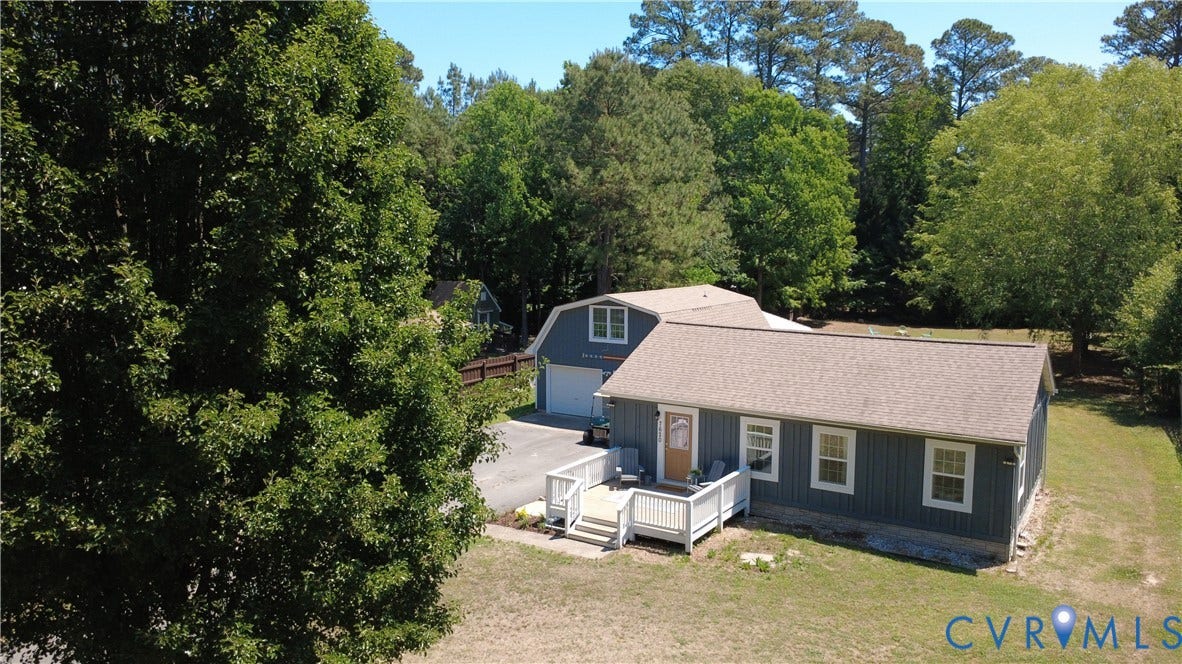 7620 Cypress Drive, Lanexa, VA 23089 Single-story residence featuring vertical siding, a paved driveway, detached two-story outbuilding, and a raised exterior deck