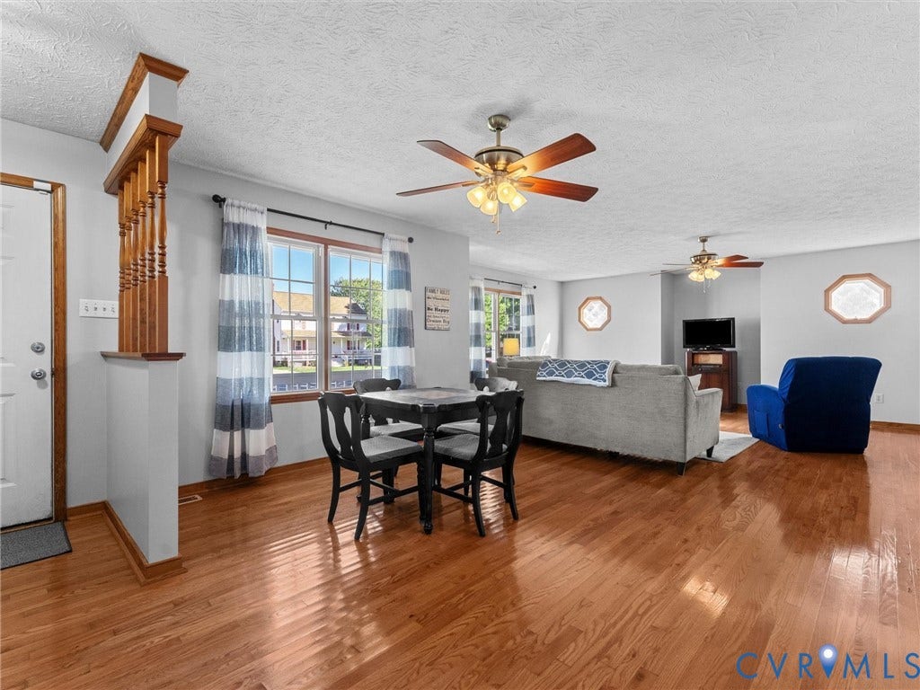 209 Taraby Drive, Hunters Run, Sandston, VA 23150 Open-concept interior featuring wood-finish flooring, half-wall spindle room divider, dual ceiling fans with integrated lighting, and multiple octagonal accent windows