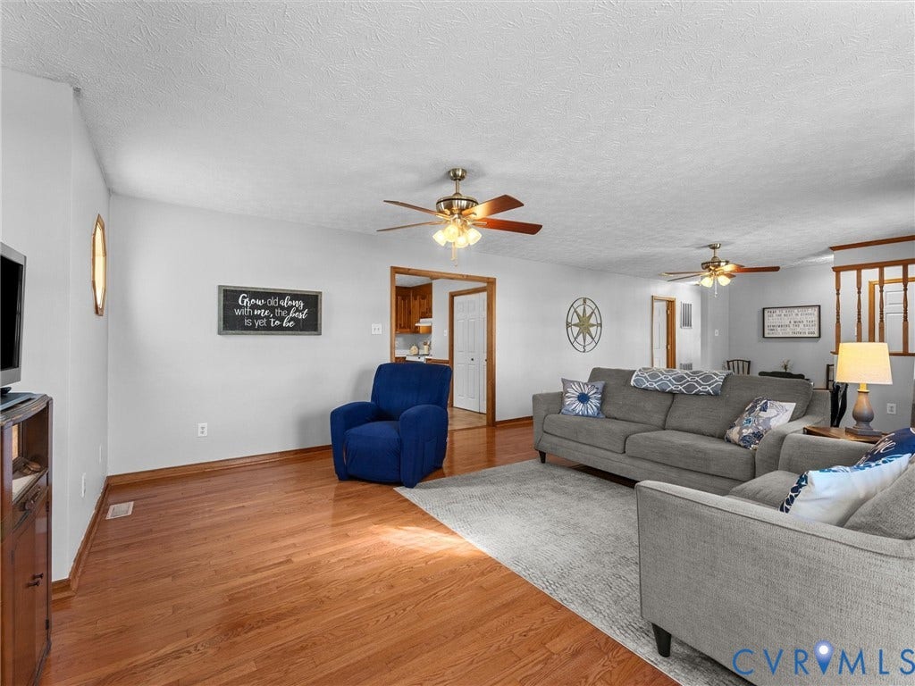 209 Taraby Drive, Hunters Run, Sandston, VA 23150 Open-concept living space featuring wood-finish flooring, dual ceiling fans with integrated lighting, and natural wood trim doorways