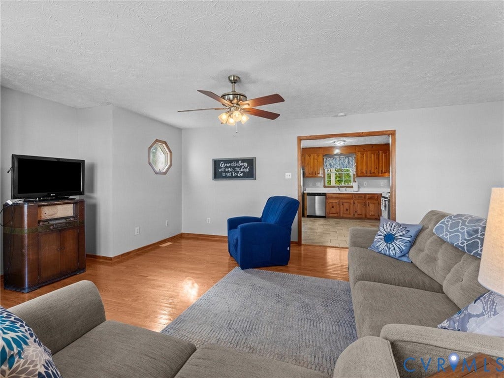 209 Taraby Drive, Hunters Run, Sandston, VA 23150 Living area featuring hardwood flooring, an octagonal accent window, and a ceiling fan with integrated light fixture