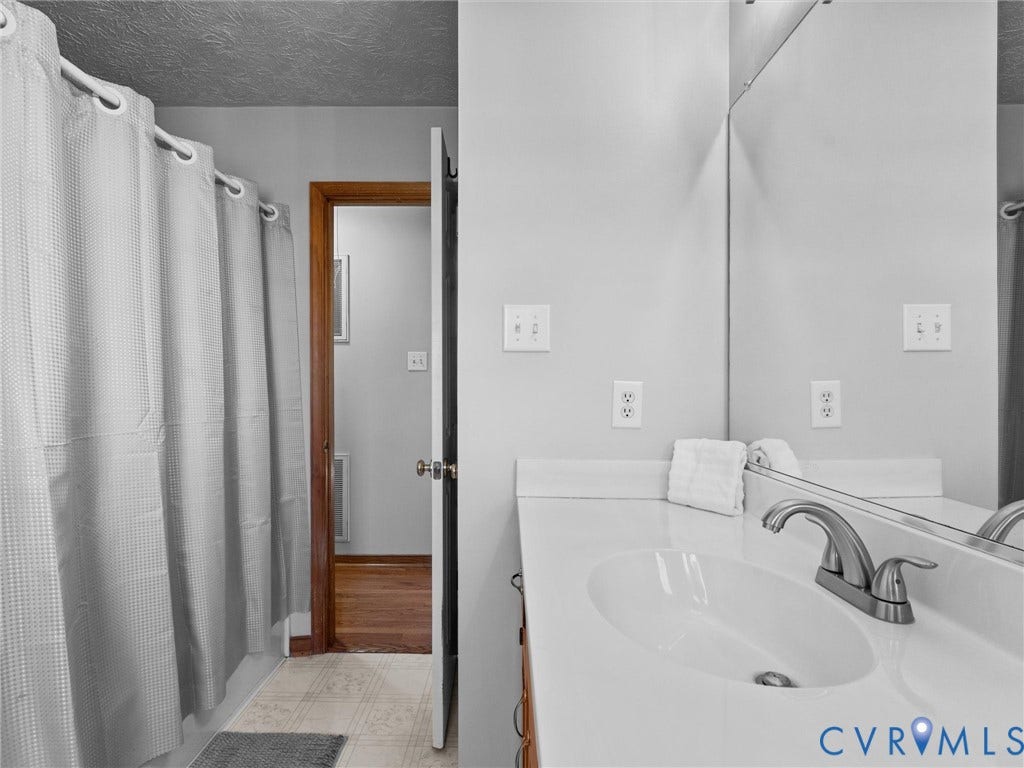 209 Taraby Drive, Hunters Run, Sandston, VA 23150 Bathroom featuring a white vanity with a molded basin, brushed nickel faucet, large wall-mounted mirror, and a tub-shower combination