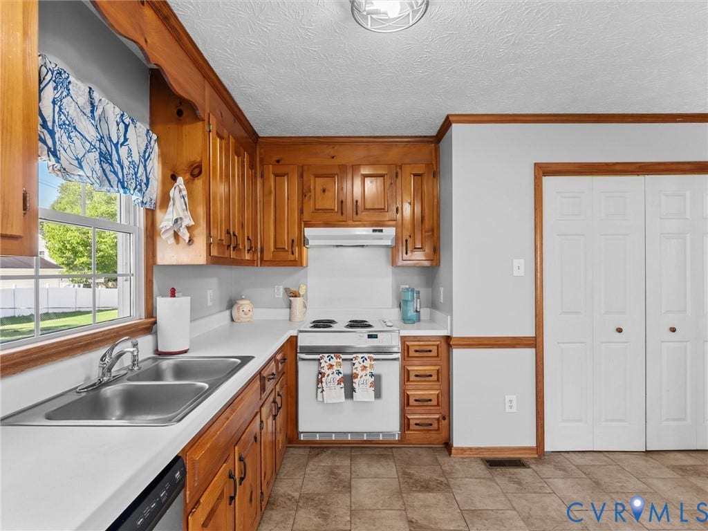 209 Taraby Drive, Hunters Run, Sandston, VA 23150 Kitchen featuring natural wood cabinetry, solid-surface countertops, dual-basin stainless steel sink, tile flooring, and bi-fold closet doors