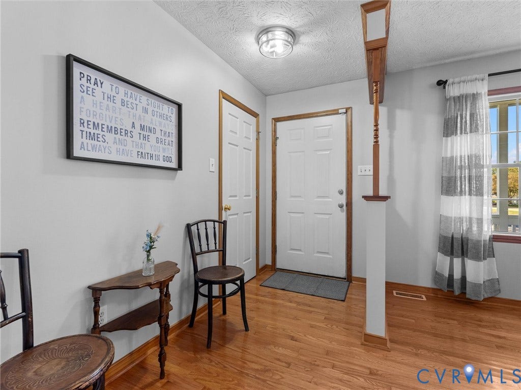 209 Taraby Drive, Hunters Run, Sandston, VA 23150 Entryway featuring wood-finish flooring, a six-panel door with wood trim, a semi-flush mount ceiling fixture, and a decorative wood column