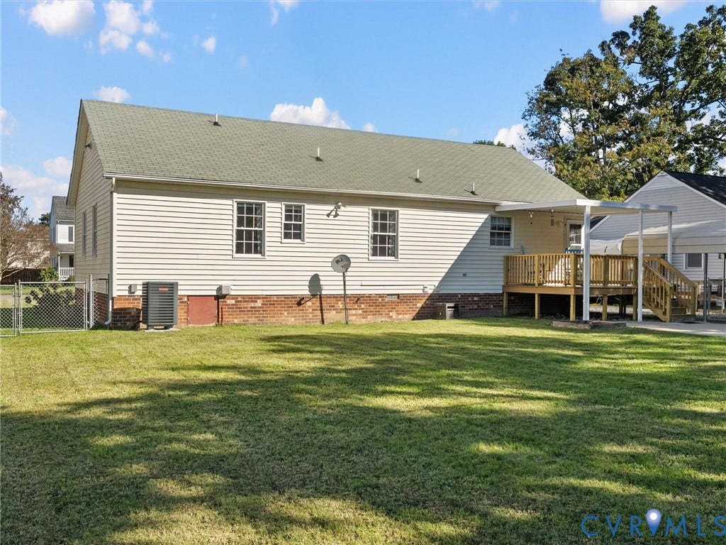 209 Taraby Drive, Hunters Run, Sandston, VA 23150 Exterior featuring light-colored horizontal siding, a partial brick facade, a shingled roof, a rear wooden deck, and a fenced backyard