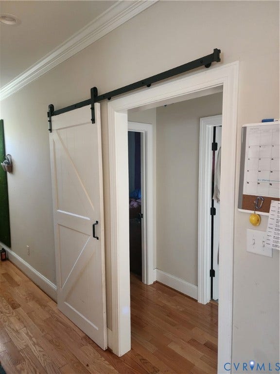 1502 N 19th Street, Church Hill, Richmond, VA 23223 White sliding barn door featuring a matte black track and hardware, complemented by wood-finish flooring and crown molding
