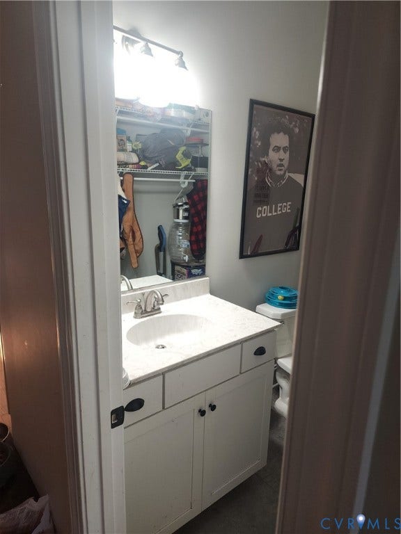 1502 N 19th Street, Church Hill, Richmond, VA 23223 Vanity featuring a white cabinet base, stone-composite countertop with an integrated oval sink, polished metal faucet, and wall-mounted vanity lighting