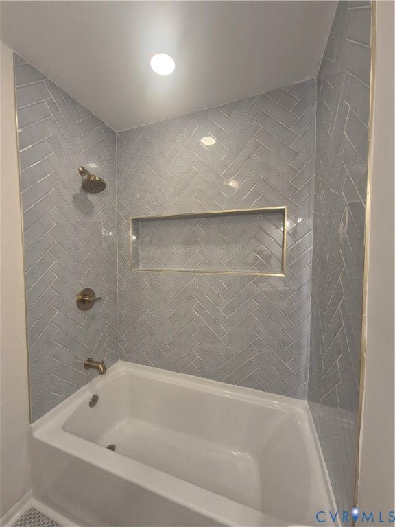17 Jarratt Court, Petersburg, VA 23803 Bathtub enclosure featuring light gray herringbone-patterned wall tile, brass-finish fixtures, and a recessed tiled niche with brass-toned trim
