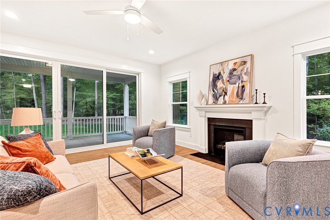 9107 Terroir Lane, Viniterra Villas, New Kent, VA 23124 Living area featuring wood-finish flooring, a fireplace with a white mantel, sliding glass doors, and a ceiling fan