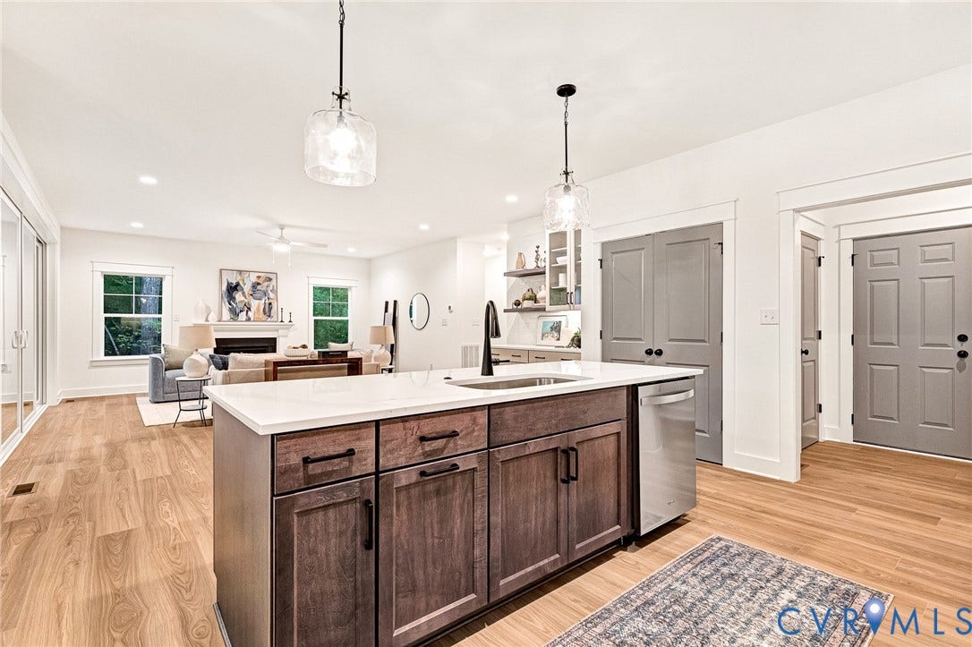 9107 Terroir Lane, Viniterra Villas, New Kent, VA 23124 Kitchen island featuring a stone countertop, an undermount sink with a matte black faucet, wood-finish cabinetry, and dual glass pendant lights