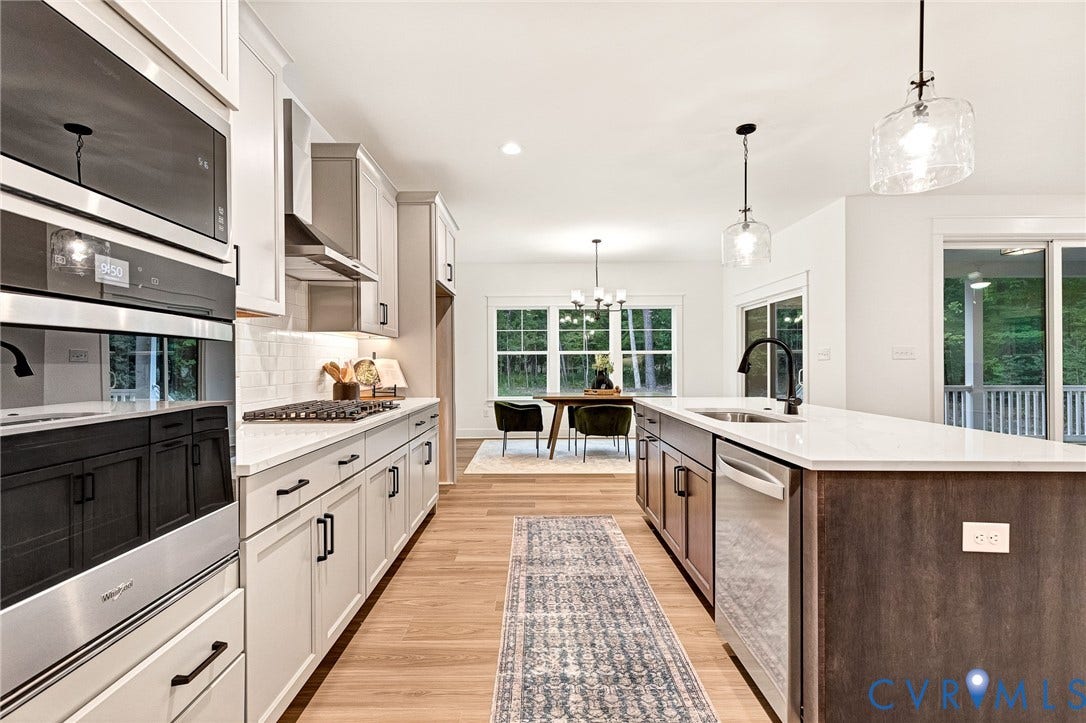 9107 Terroir Lane, Viniterra Villas, New Kent, VA 23124 Kitchen featuring light-toned shaker cabinetry, a contrasting dark-finish kitchen island with a stone-surface countertop, built-in stainless steel double ovens, wood-finish flooring, and glass pendant lighting