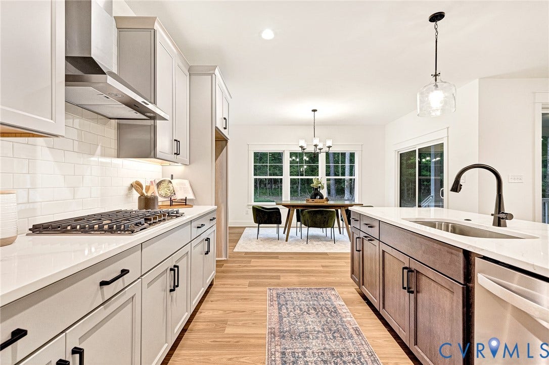 9107 Terroir Lane, Viniterra Villas, New Kent, VA 23124 Kitchen featuring light-toned cabinetry, quartz countertops, subway tile backsplash, stainless steel gas cooktop with range hood, and a center island with under-mount sink and matte black fixture