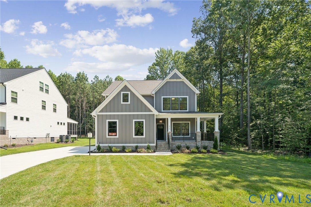 9107 Terroir Lane, Viniterra Villas, New Kent, VA 23124 Two-story exterior featuring vertical board-and-batten siding, a stone foundation, a covered front porch with stone columns, and dark-framed windows