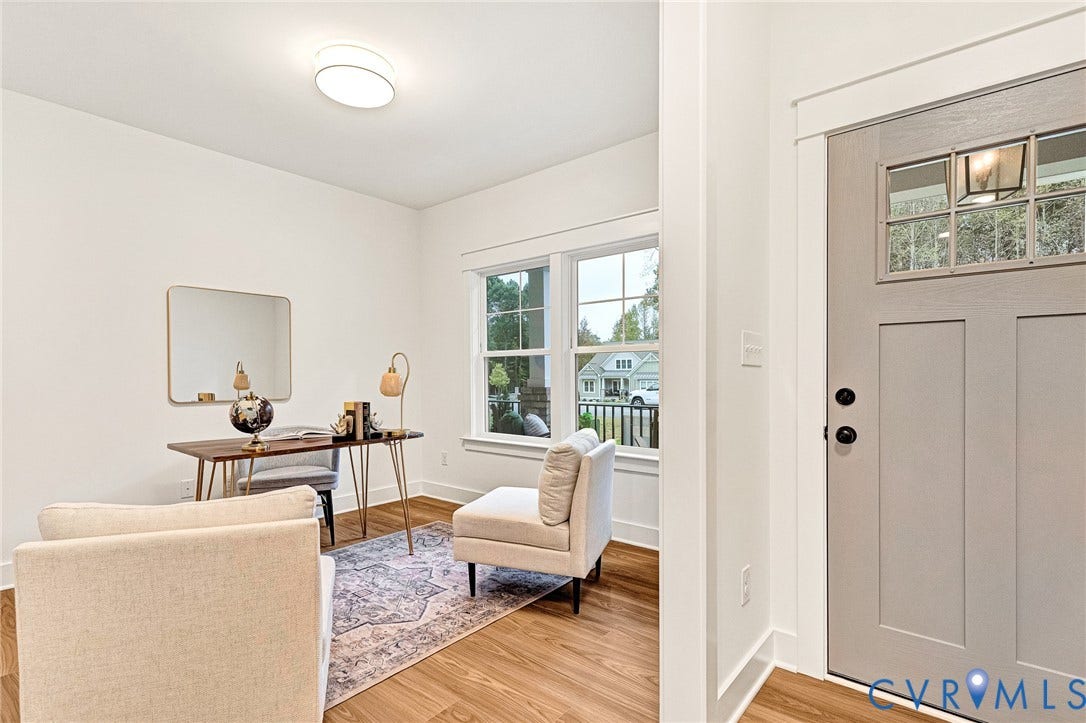 9107 Terroir Lane, Viniterra Villas, New Kent, VA 23124 Neutral-toned solid core door with a multi-pane glass insert, wood-finish flooring, crisp white wall trim, and multi-pane windows with detailed framing