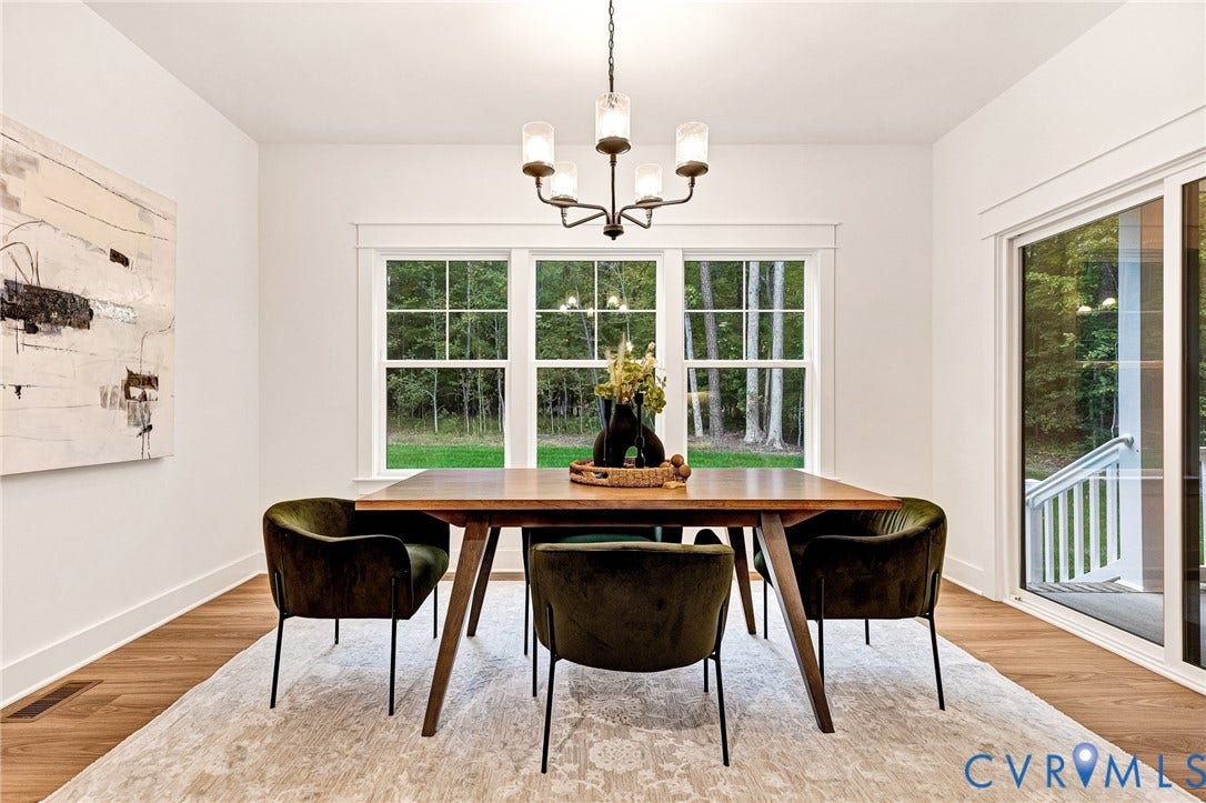 9107 Terroir Lane, Viniterra Villas, New Kent, VA 23124 Dining space featuring wood-finish flooring, a multi-light metal chandelier with glass shades, grid-patterned windows, and a large sliding glass door