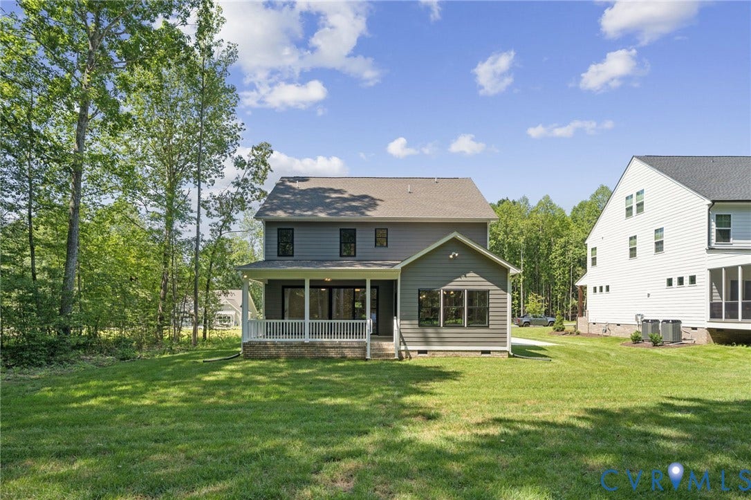 9107 Terroir Lane, Viniterra Villas, New Kent, VA 23124 Two-story residence featuring horizontal lap siding, a rear covered porch with white railing, and an expansive lawn