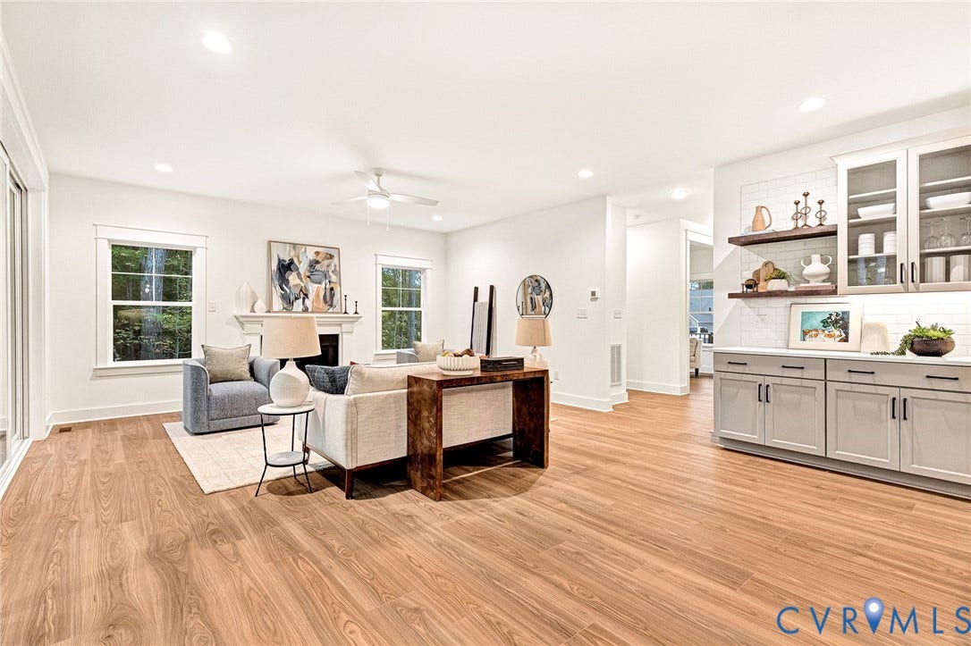 9107 Terroir Lane, Viniterra Villas, New Kent, VA 23124 Open-concept interior featuring wood-finish flooring, recessed lighting, a fireplace with a decorative mantel, and built-in cabinetry with glass-front uppers and floating wood shelves