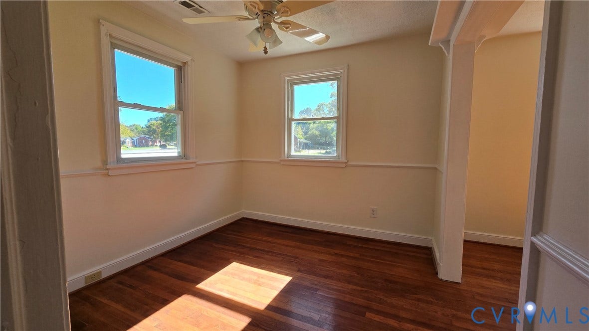 38 Eastlake Drive, Sandston, Sandston, VA 23150 Room featuring dark-toned wood-finish flooring, white chair rail molding, dual windows with white trim, and a ceiling-mounted fan with integrated lighting