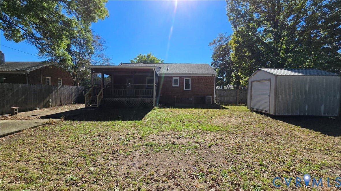 38 Eastlake Drive, Sandston, Sandston, VA 23150 Rear exterior featuring a brick facade, covered wood deck, wood privacy fencing, and a detached metal storage building