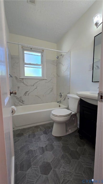 38 Eastlake Drive, Sandston, Sandston, VA 23150 Bathroom featuring gray hexagonal floor tile, white tub surround with stone-patterned tiling, wall-mounted vanity, and a framed mirror