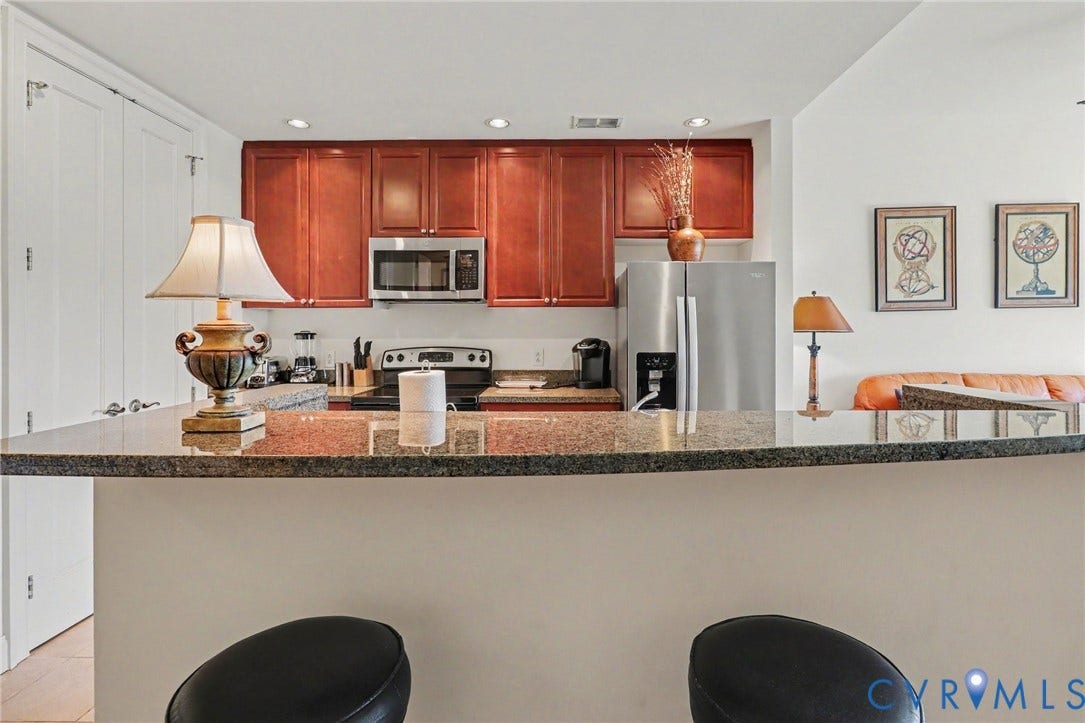 301 Virginia Street, #U1712, Richmond, VA 23219 Kitchen featuring wood cabinetry, stone countertops, stainless steel appliances, and a breakfast bar