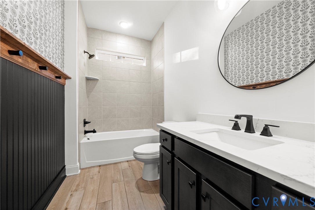 2613 Lilybank Place, NewMarket At RounTrey, Midlothian, VA 23112 Bathroom featuring wood-finish flooring, a vanity with a light-toned countertop, matte black hardware, vertical wainscoting, and an oval wall-mounted mirror