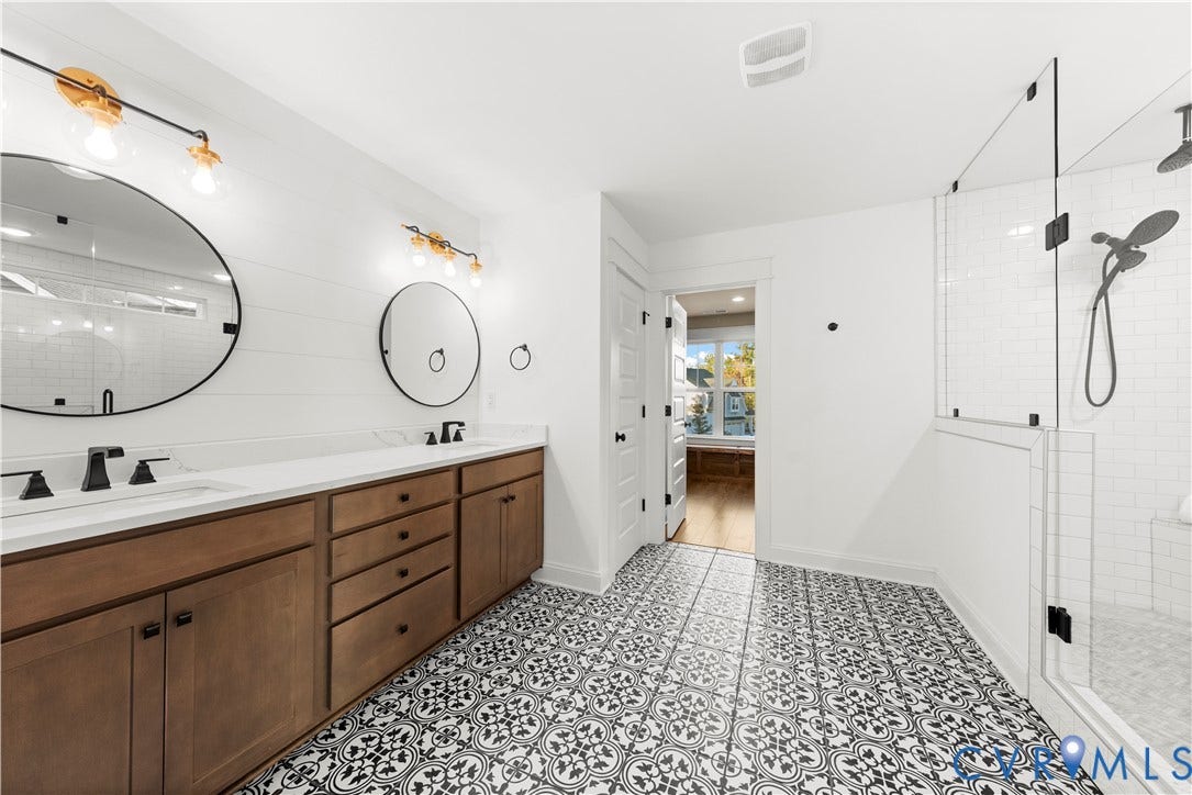 2613 Lilybank Place, NewMarket At RounTrey, Midlothian, VA 23112 Double vanity with wood-finish cabinetry, patterned floor tile, glass-enclosed shower, round wall-mounted mirrors, and matte black hardware