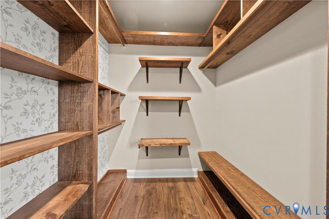 2613 Lilybank Place, NewMarket At RounTrey, Midlothian, VA 23112 Walk-in storage space featuring built-in wood-finish shelving, wall-mounted floating wood shelves, patterned wallpaper accent, and wood-finish flooring